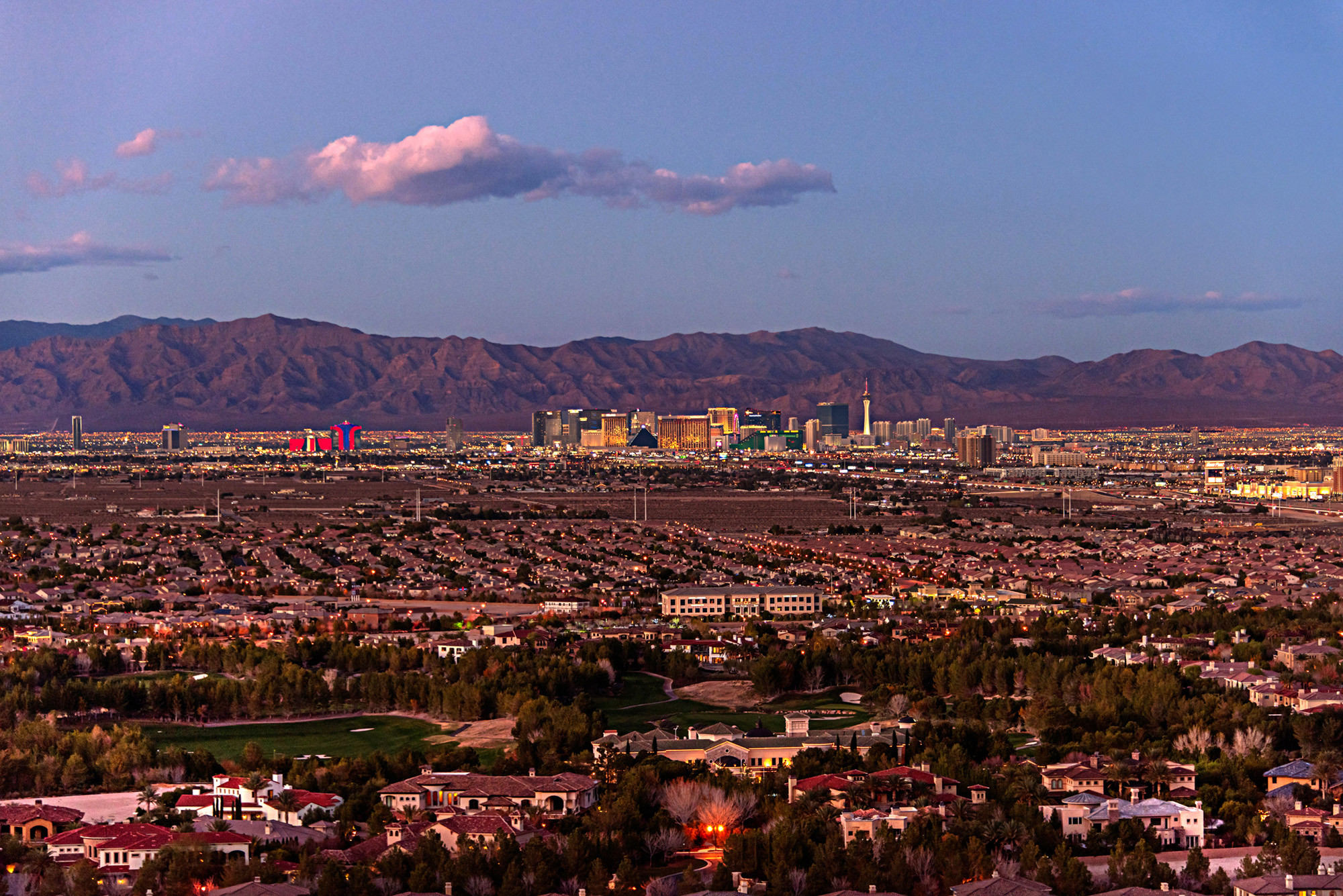 Luxurious neighborhood with city skyline and mountain views at dusk.