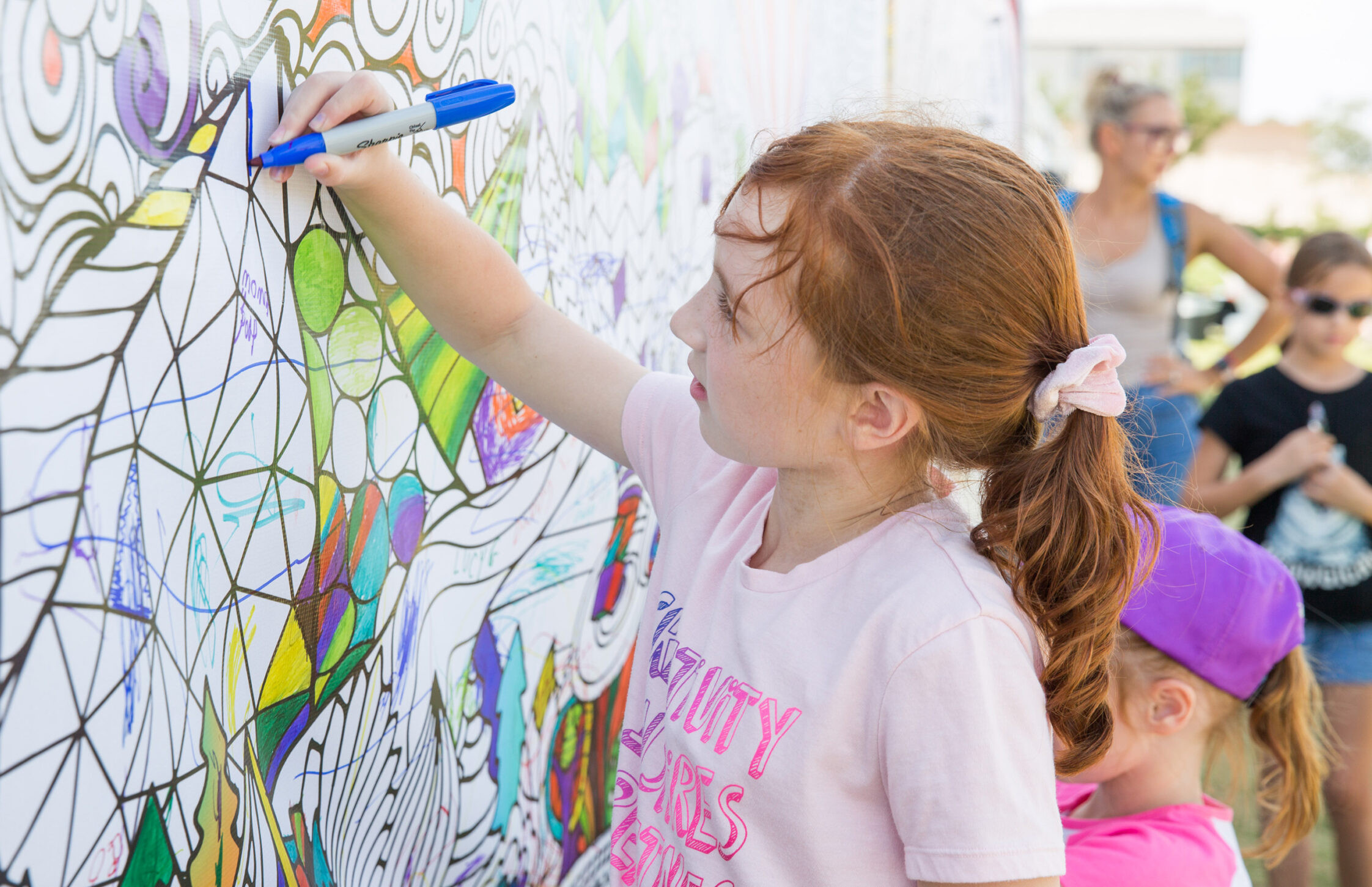 Community kids coloring mural at outdoor event, family fun and artistic activities.